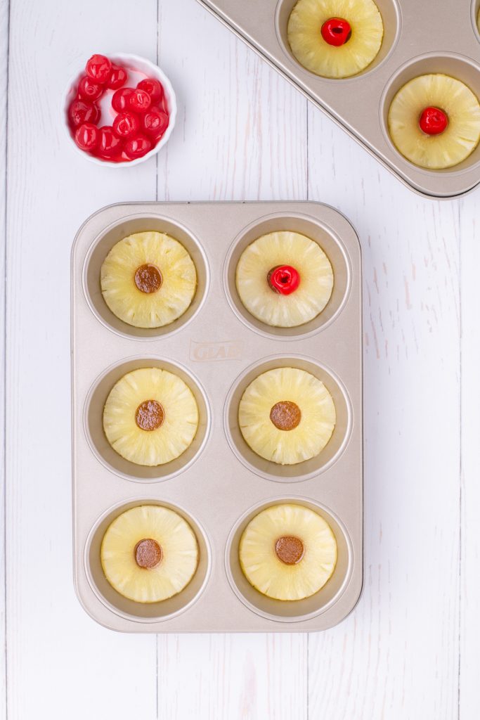 Muffin tin topped with pineapple ring and a cherry before adding batter.