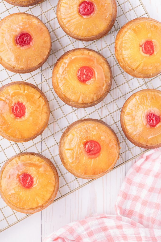 Mini pineapple upside down cupcakes on a cooling rack.