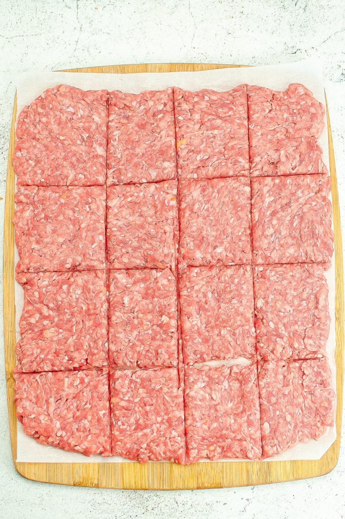 Ground hamburger shaped in a rectangle on a cutting board.