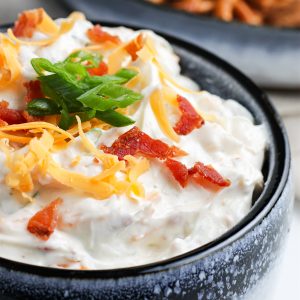 A small serving bowl with a blue rim filled with bacon cheddar ranch dip.