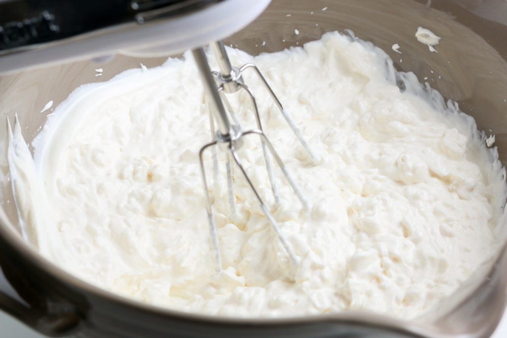 Mixing cream cheese and sour cream in a mixing bowl.