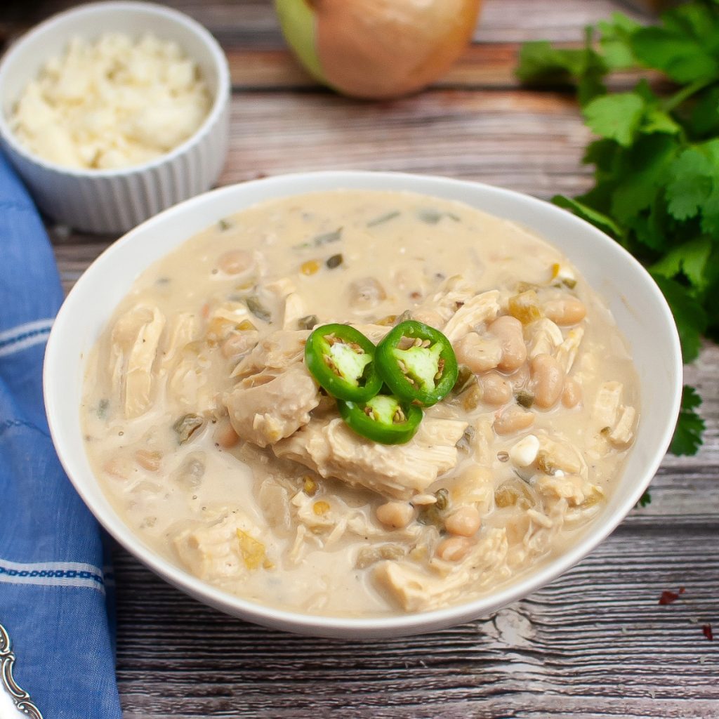 Chicken White Chili in a white bowl topped with sliced jalapenos.