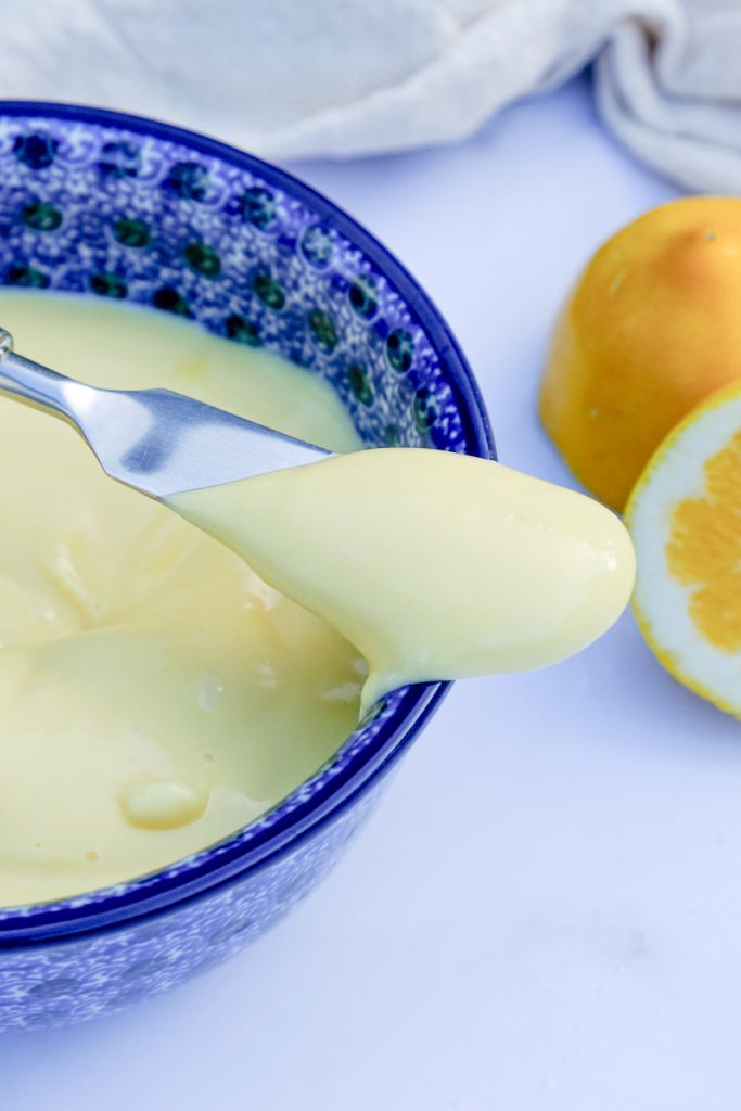 A small knife with homemade mayonnaise resting on the side of a blue jar. 