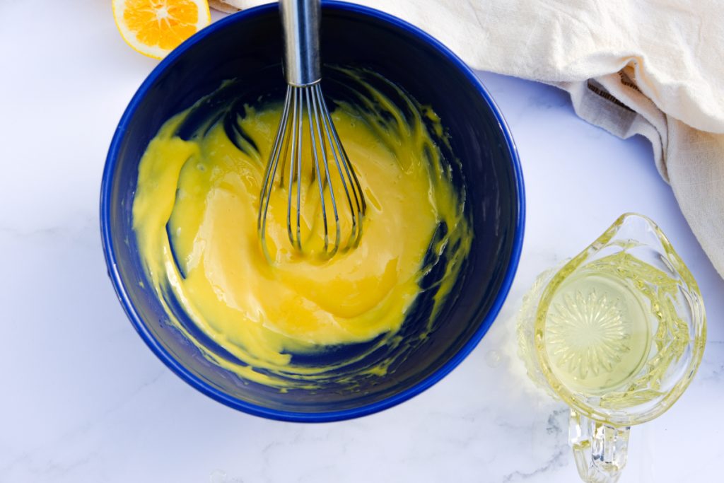 Whisking homemade mayonnaise in a blue mixing bowl. 