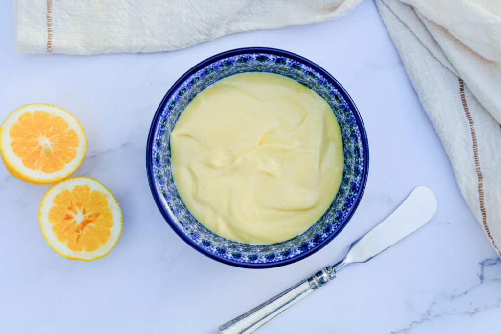 Whole 30 homemade mayonnaise in a small blue serving bowl with a knife on the side.