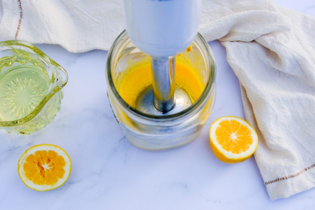 Mixing egg yolks with mustard, salt, and Dijon mustard with an immersion hand blender.  