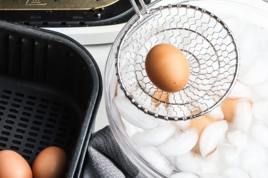 Cooked eggs being placed in an ice bath.