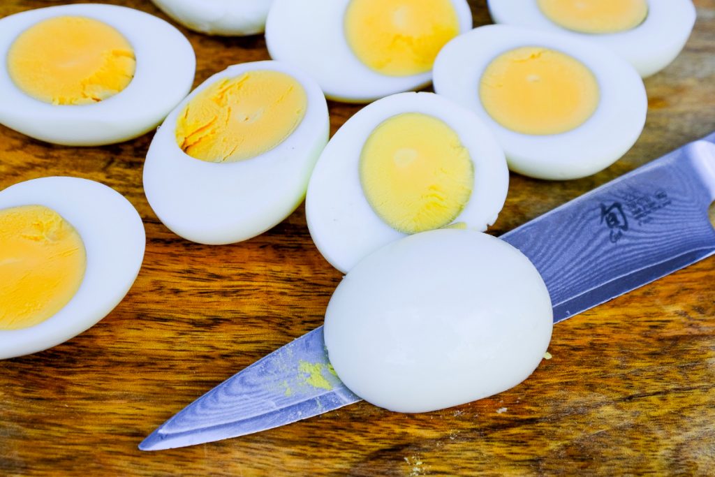 Sliced hard-boiled eggs on a brown cutting board. 