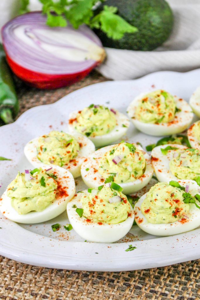 A white platter with avocado deviled eggs ready to eat. 