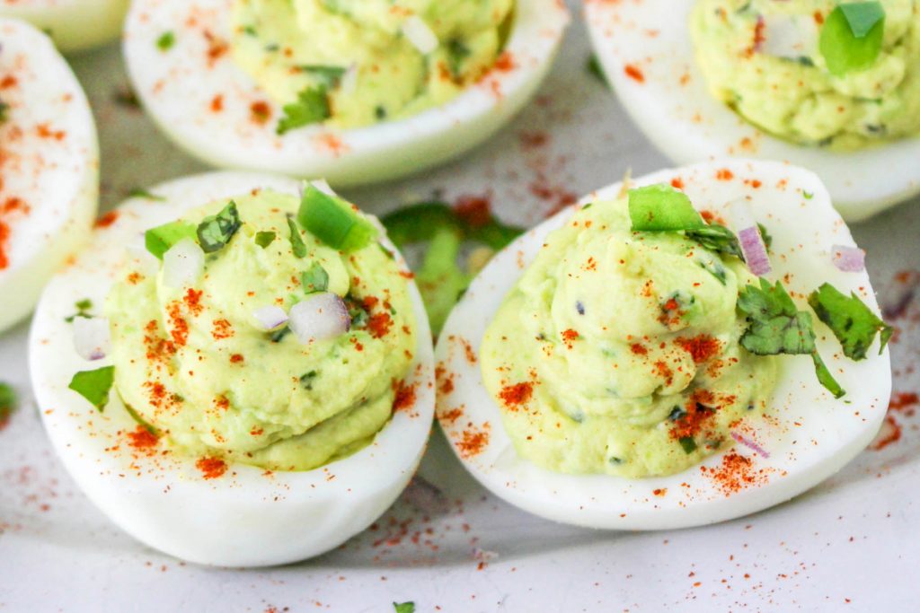 Garnishing eggs with paprika, chopped cilantro and diced jalapenos. 