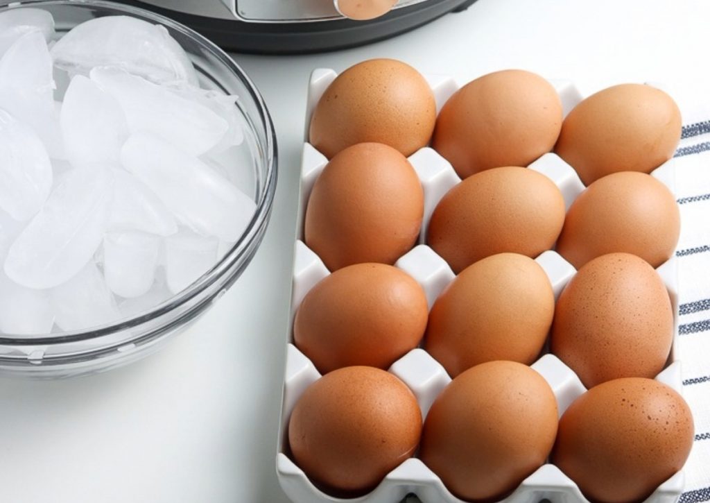 Hard boiled eggs in a tray with ice on the side in a clear bowl. 