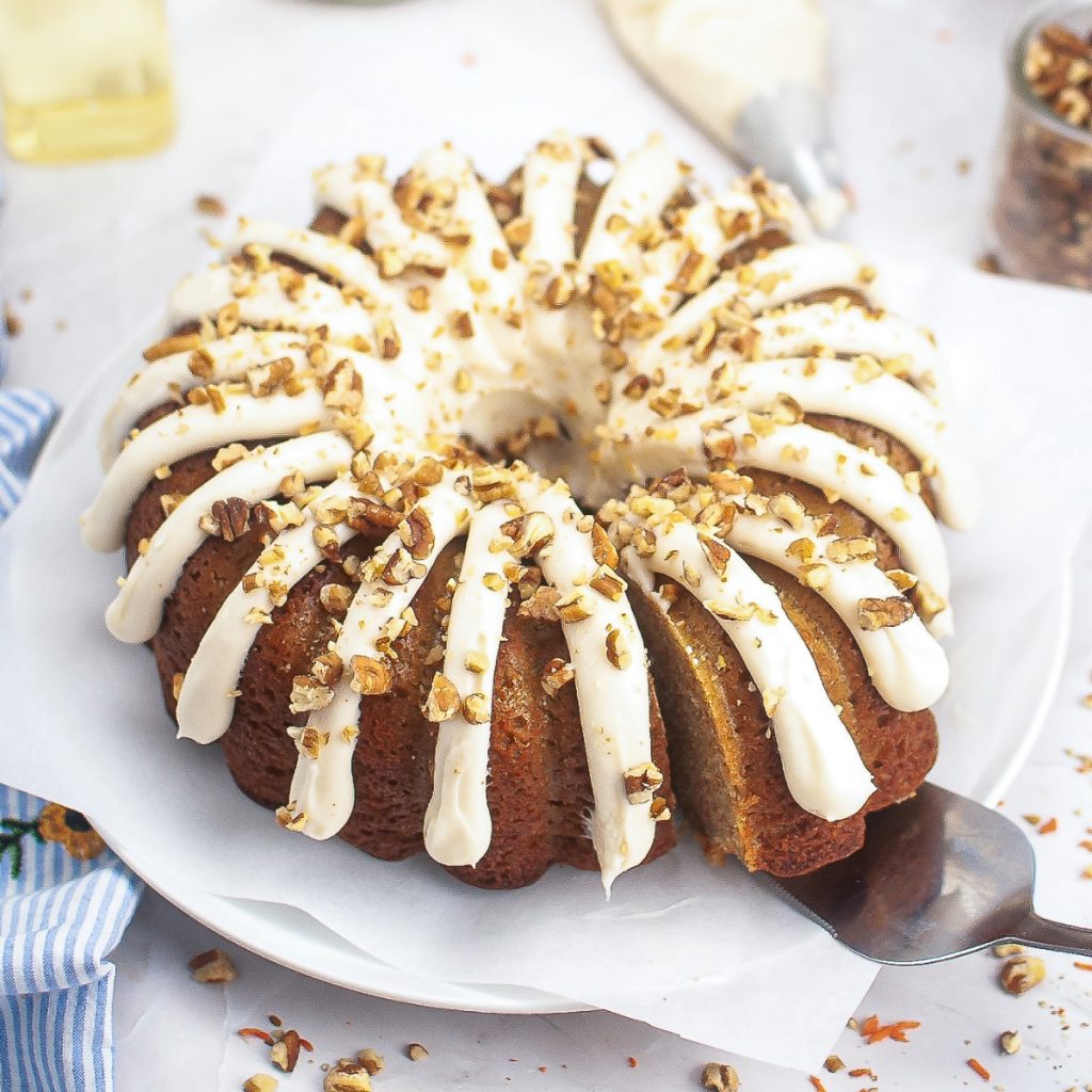 Homemade bundt cake topped with cream cheese frosting and topped with chopped walnuts.