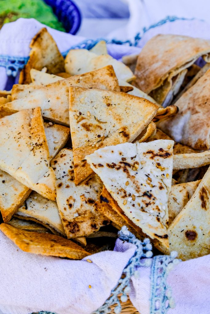 Homemade pita chips in a basket lined with a tan napkin.