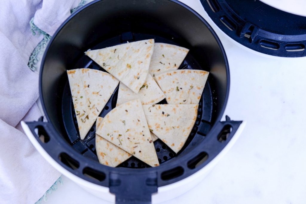 Sliced pita bread in the center of an air fryer basket.