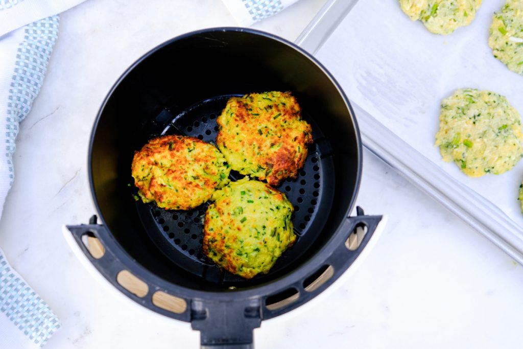 Air fried zucchini fritters in the insert of an air fryer.
