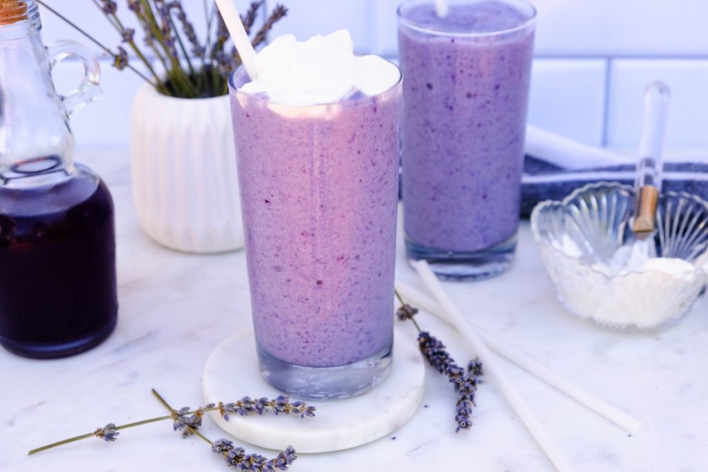 Whipped cream on top of a glass of lavender frappuccino. 