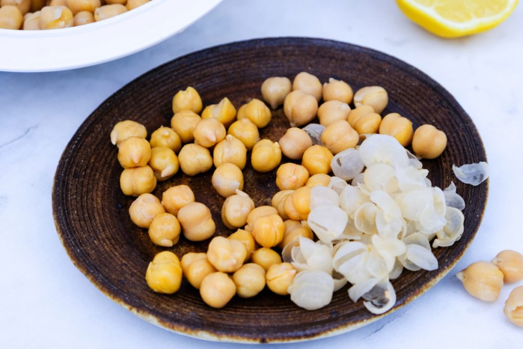 Chickpeas on a brown plate with the skins removed. 