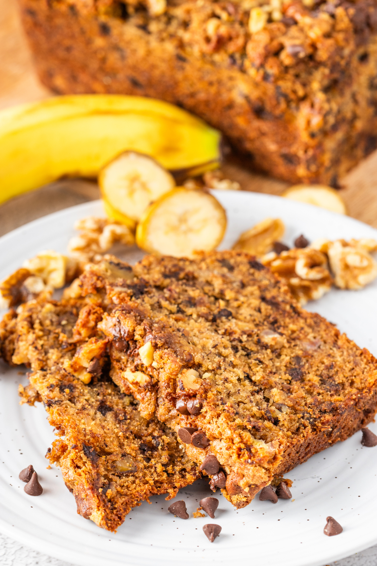 Sliced banana bread with chocolate chips on a white serving plate. 