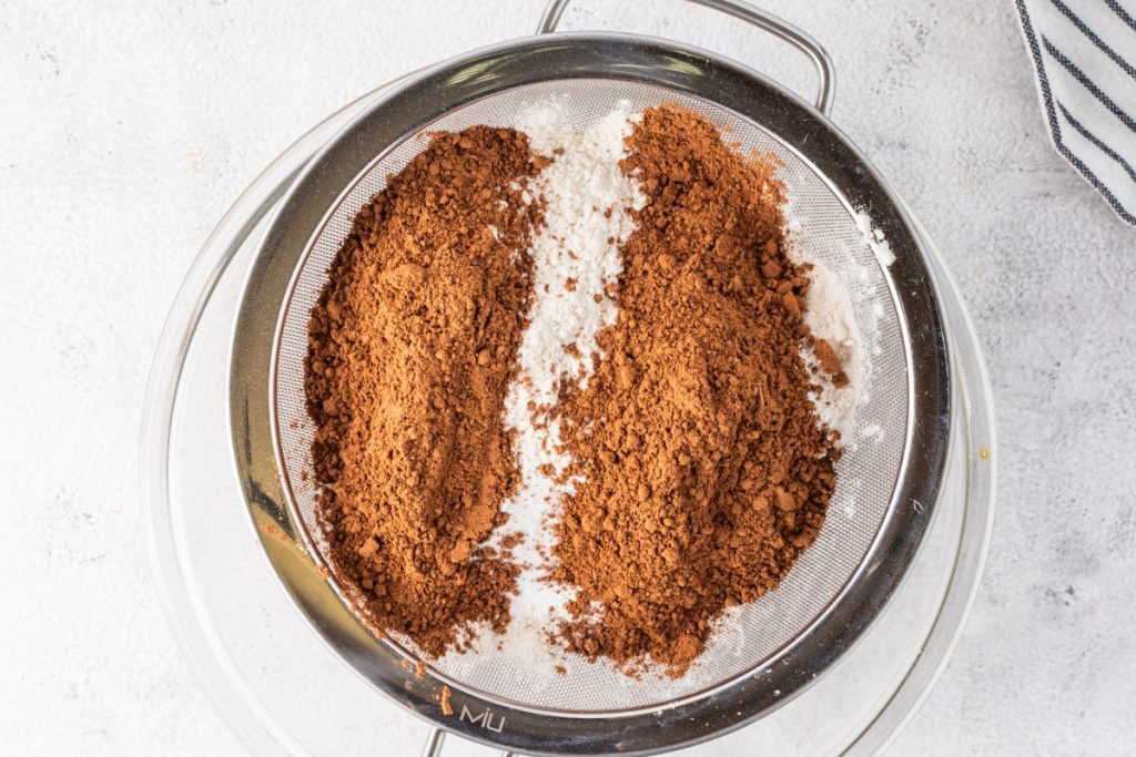 Sifting dry ingredients for a homemade chocolate cake.