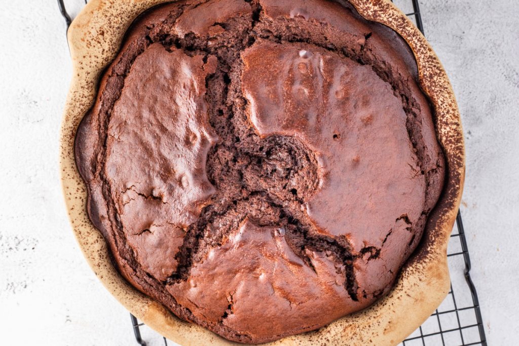 Baked chocolate cake in it's pan cooling on a baking sheet.