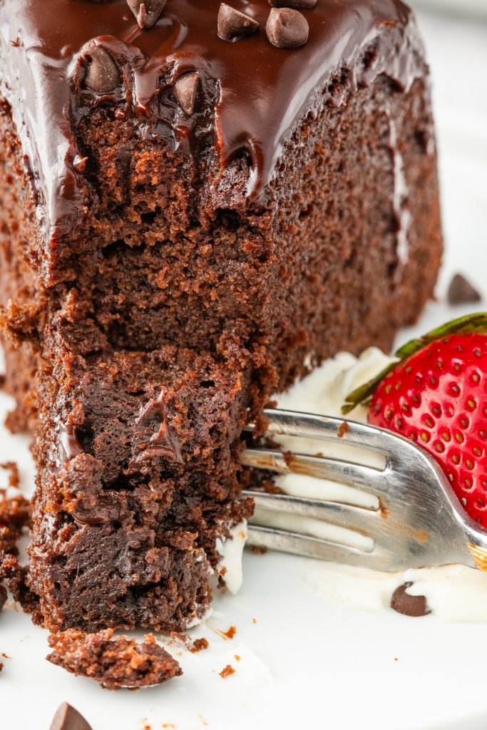 A white plate with a forkful of cake before eating.