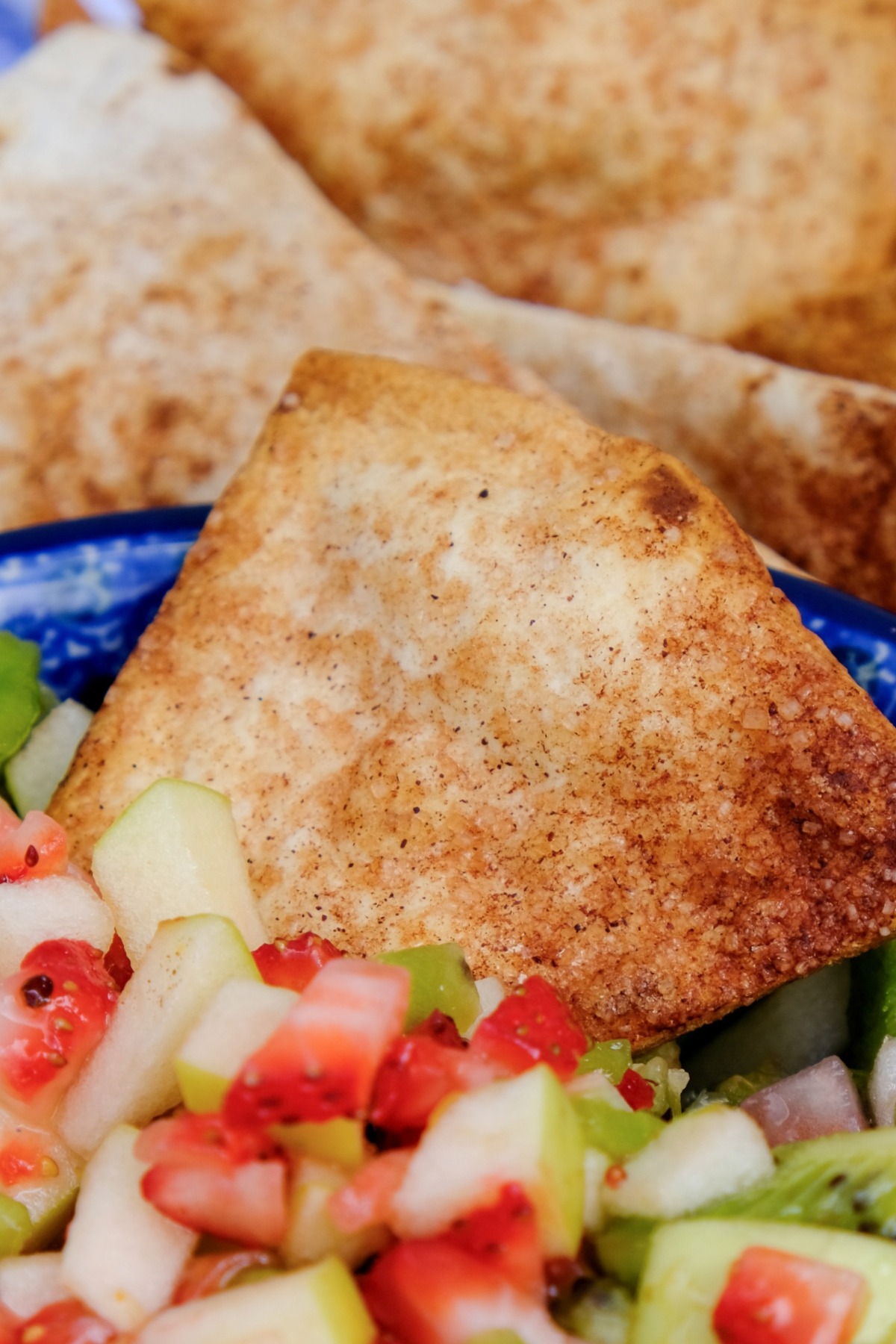 A tortilla chip dipped in fruit salsa. 