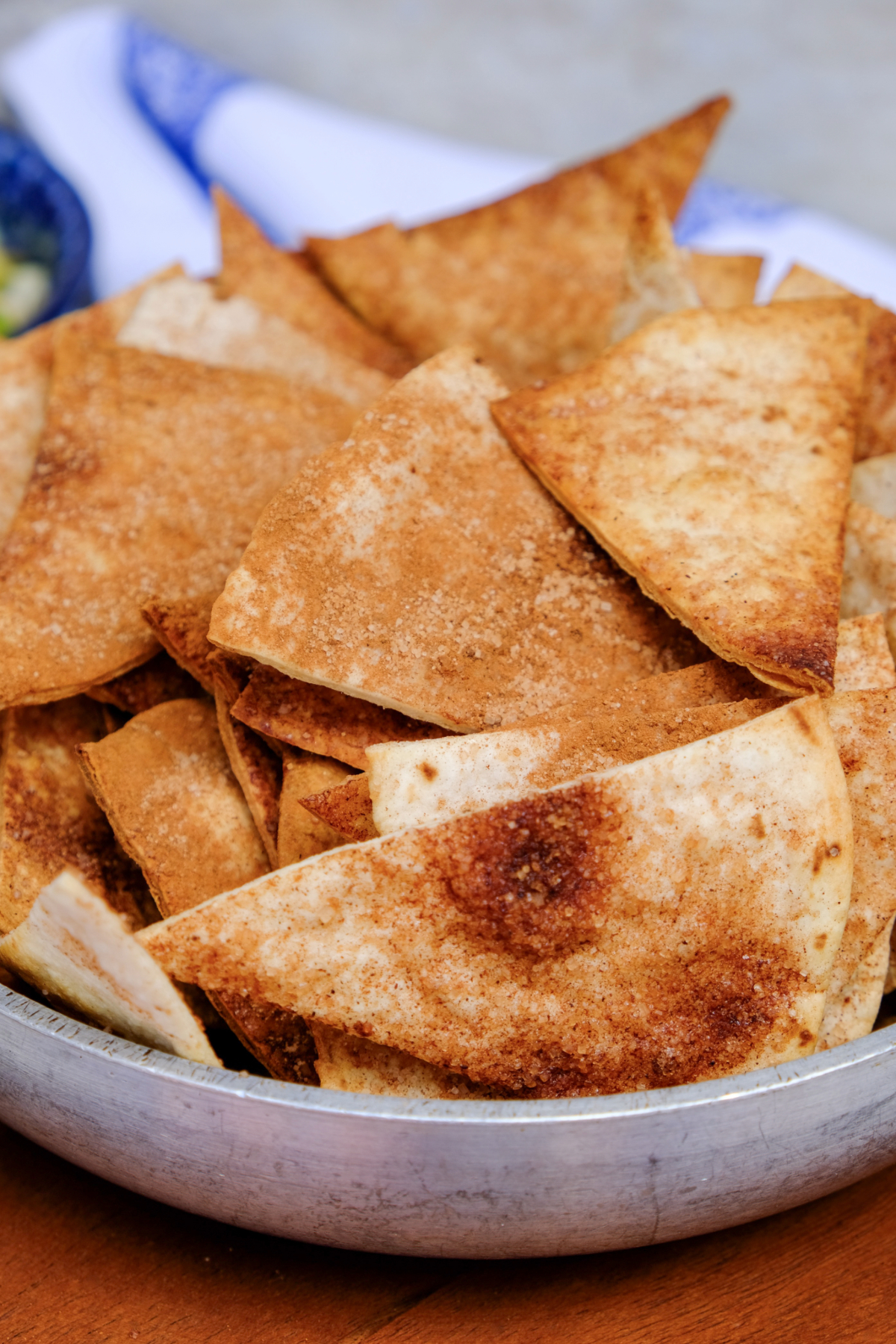 Crispy baked tortilla chips topped with cinnamon sugar in a tin bowl. 