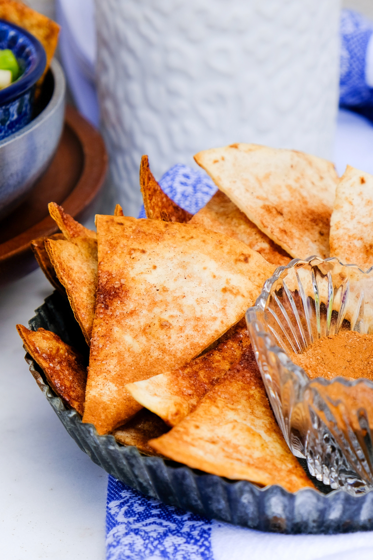 Homemade cinnamon tortilla chips on a tin tray with cinnamon sugar on the side. 