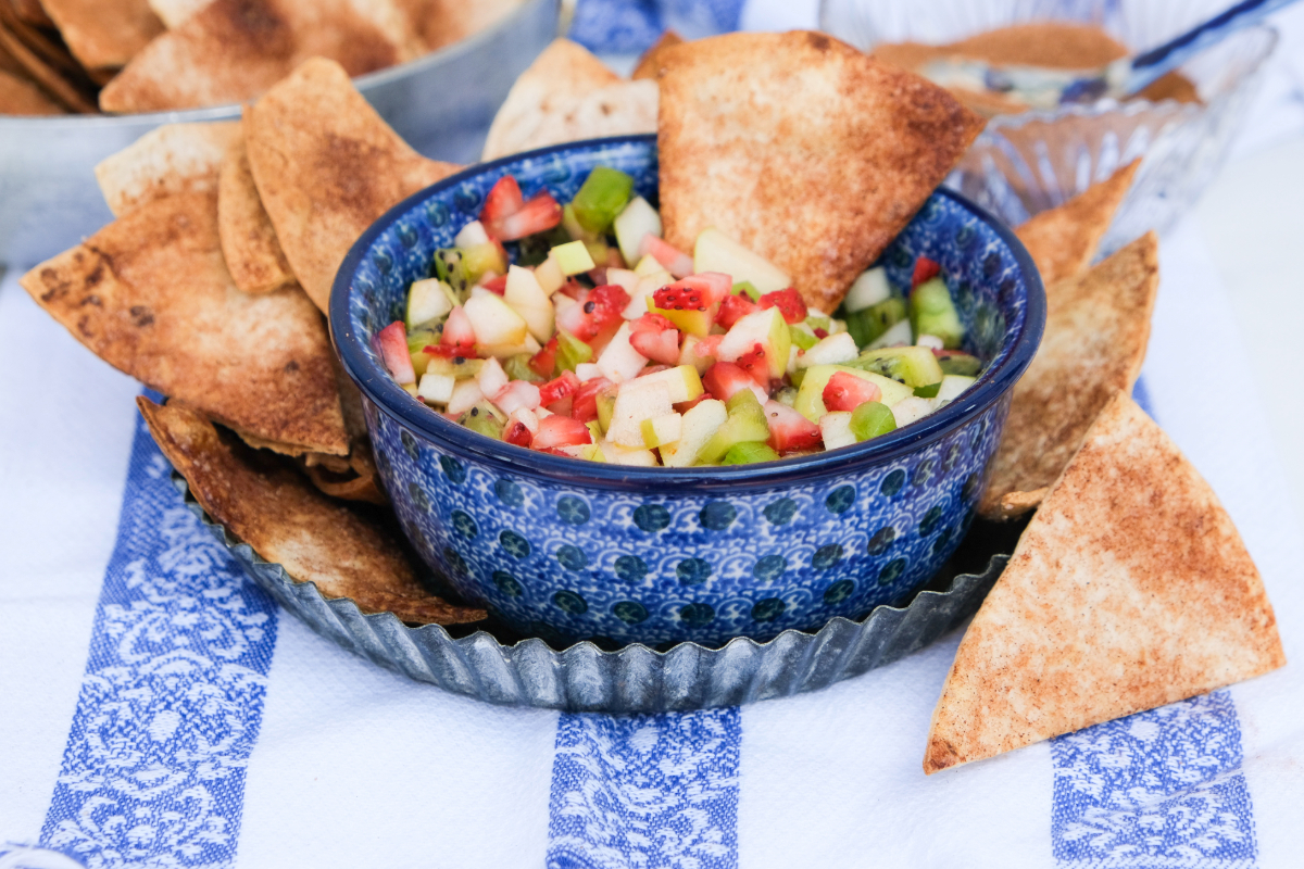 Fruit salsa in a small blue bowl with cinnamon chips on the side. 