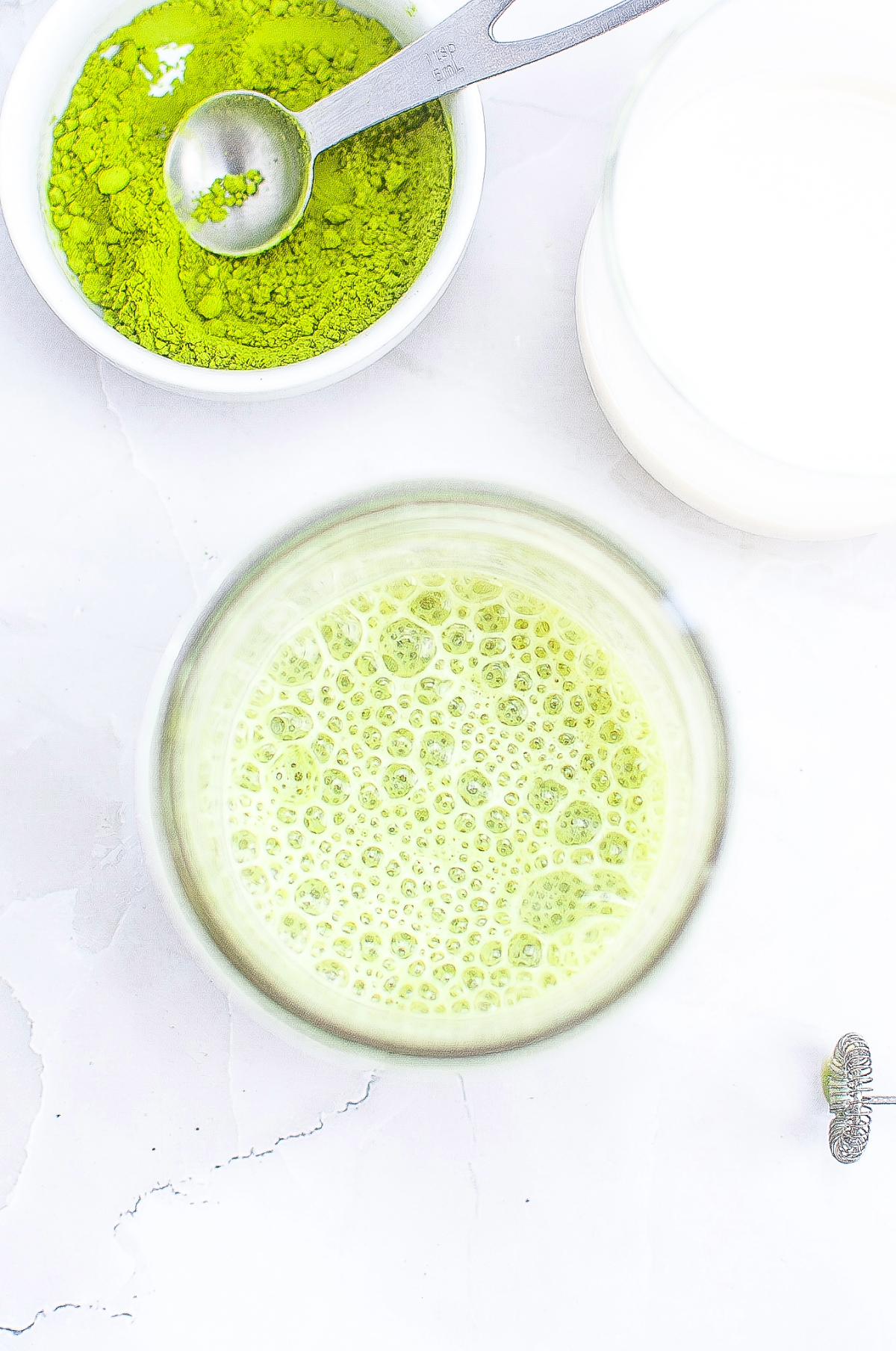 Oatmilk added to matcha mixed with a hand frother. 