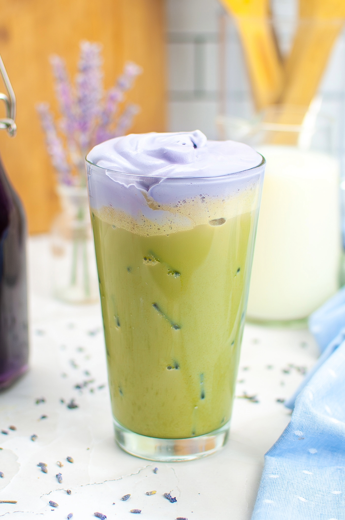 A clear glass with iced matcha topped with lavender cream. 