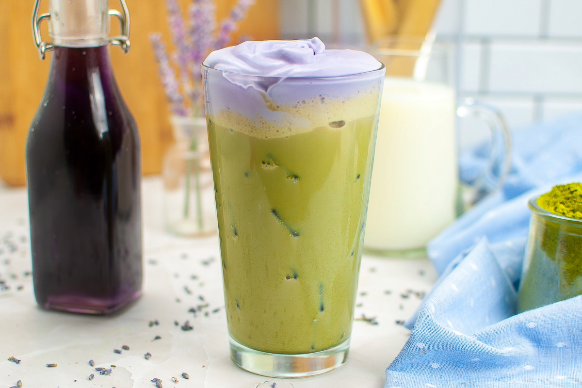 Copycat Starbucks matcha latte drink in a clear glass with matcha on the side. 