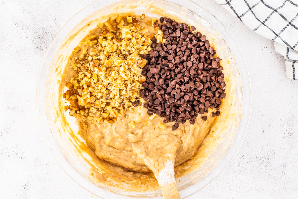 Wet ingredients for banana bread with walnuts and chocolate chips in a mixing bowl. 
