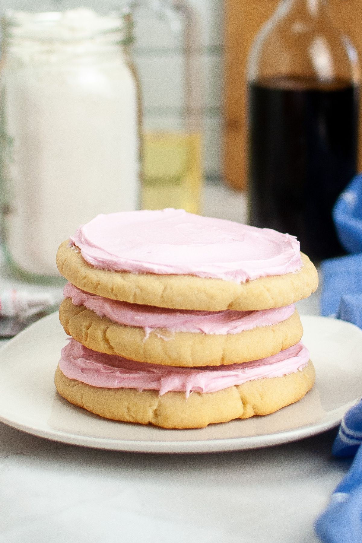 Three copycat Crumbl Pink Sugar Cookies stacked on top of each other on a small plate.