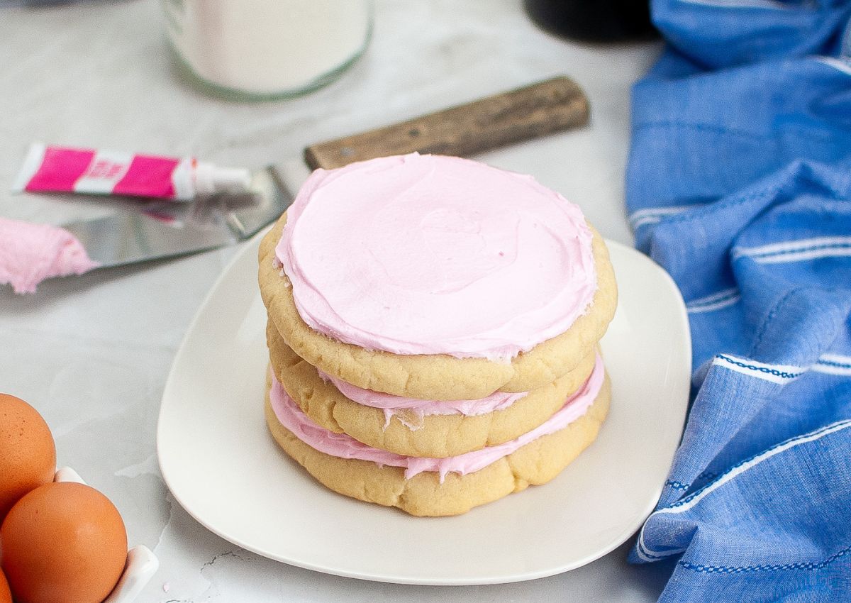 Three copycat Crumbl Pink Sugar Cookies stacked on top of each other on a small plate.