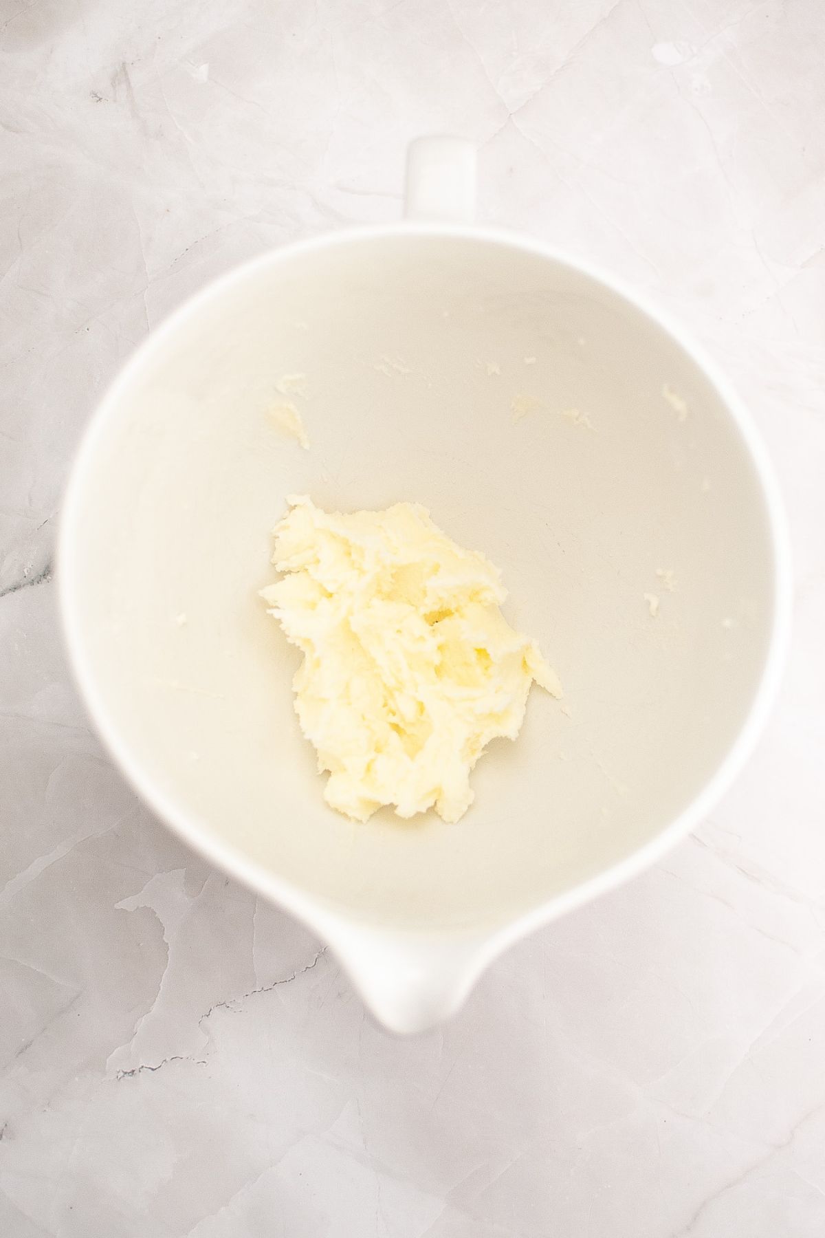 Butter and sugar being creamed together in a large bowl.