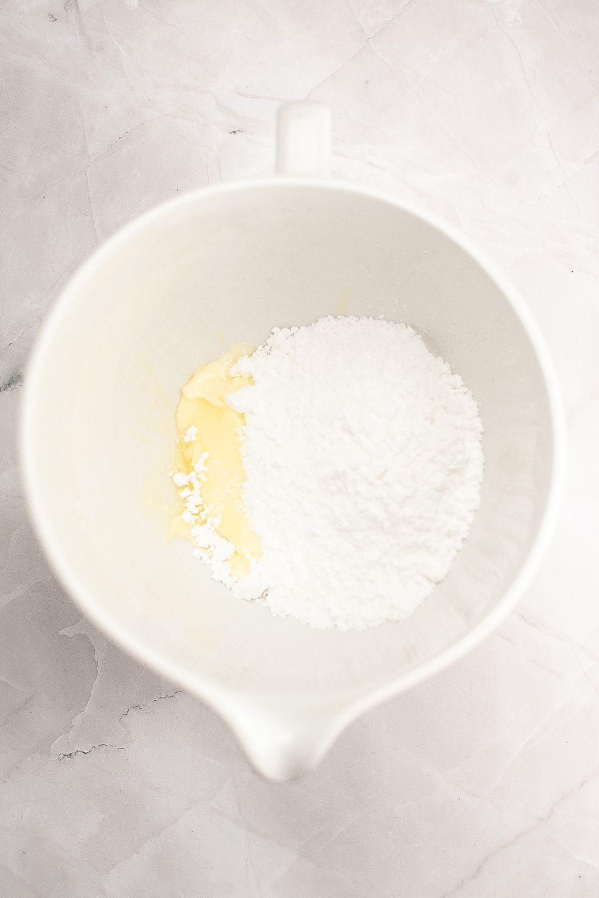 Powdered sugar and butter being mixed together in a mixing bowl.