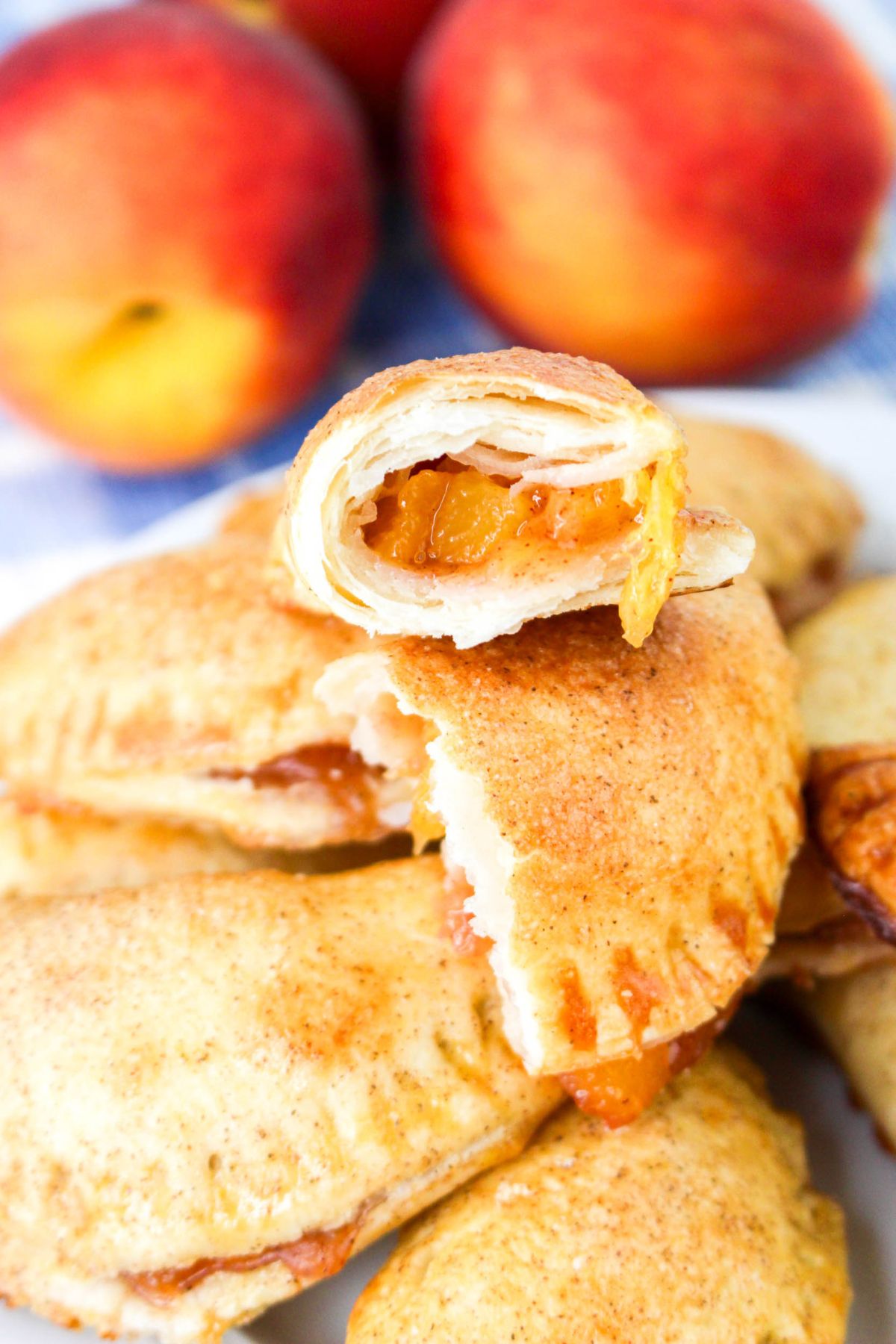 Peach hand pies stacked on a plate, with the top one broken in half.