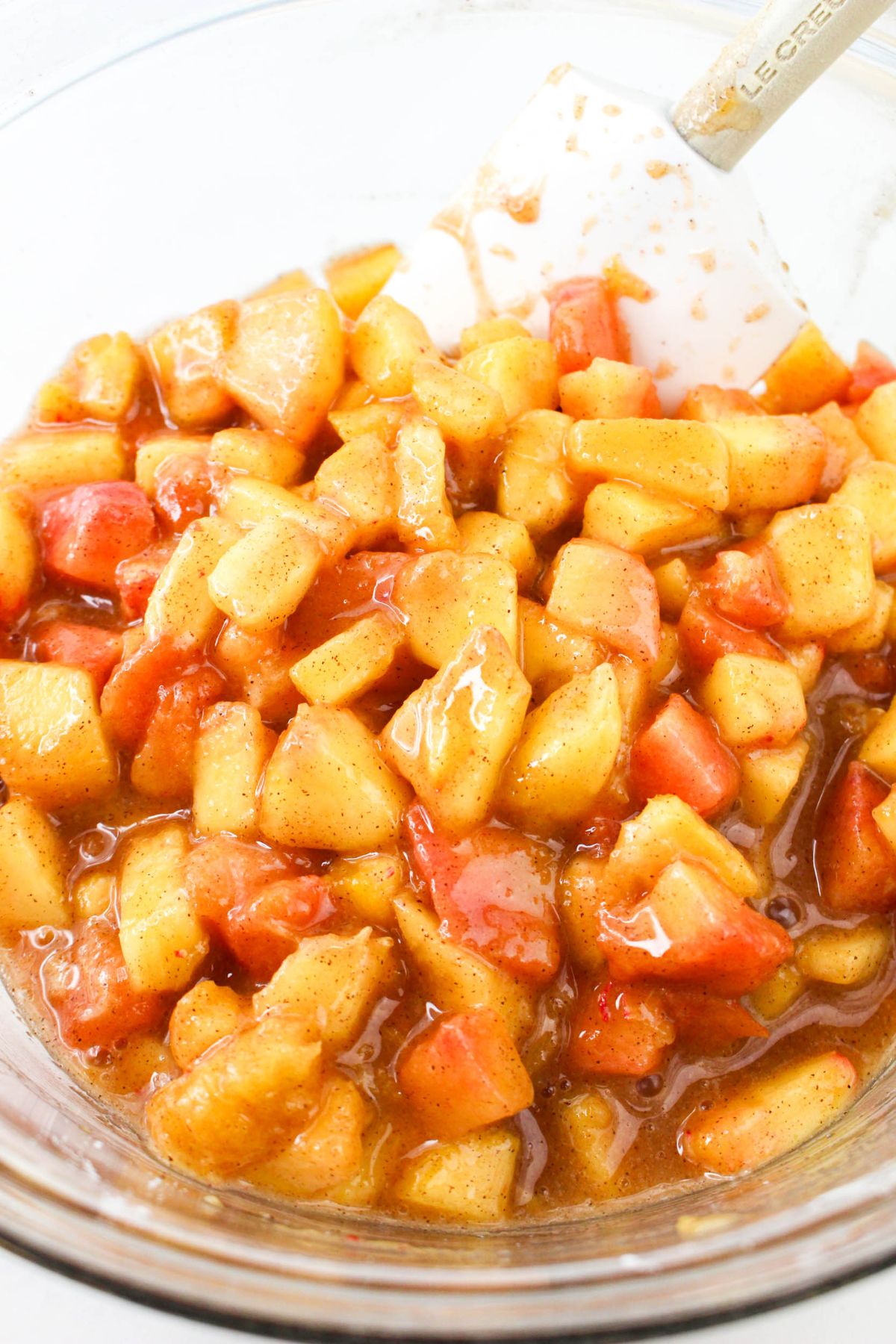 Glass mixing bowl filled with homemade peach pie filling.