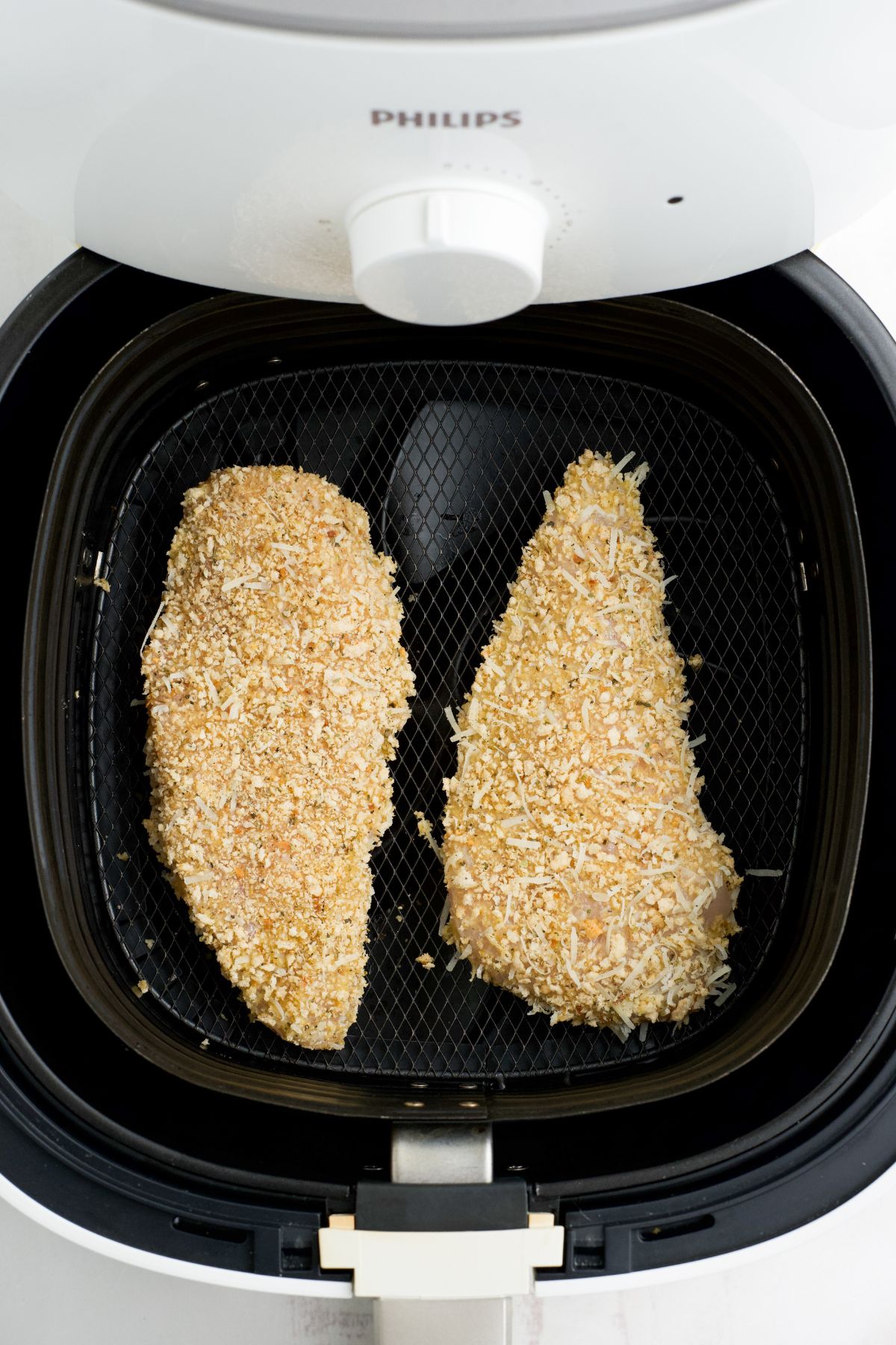 Breaded chicken in a air fryer basket ready to cook.