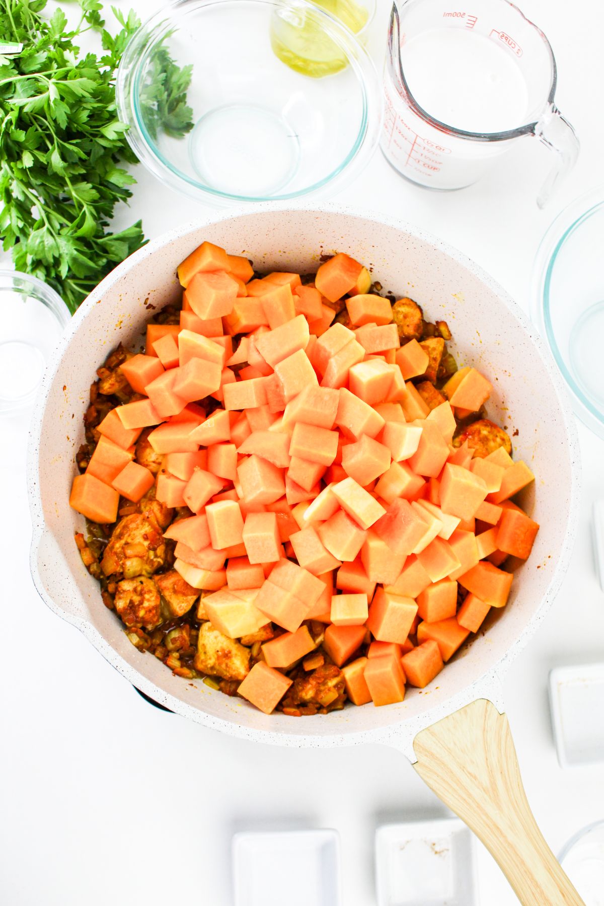 Chicken and pumpkin being added to a large pot.