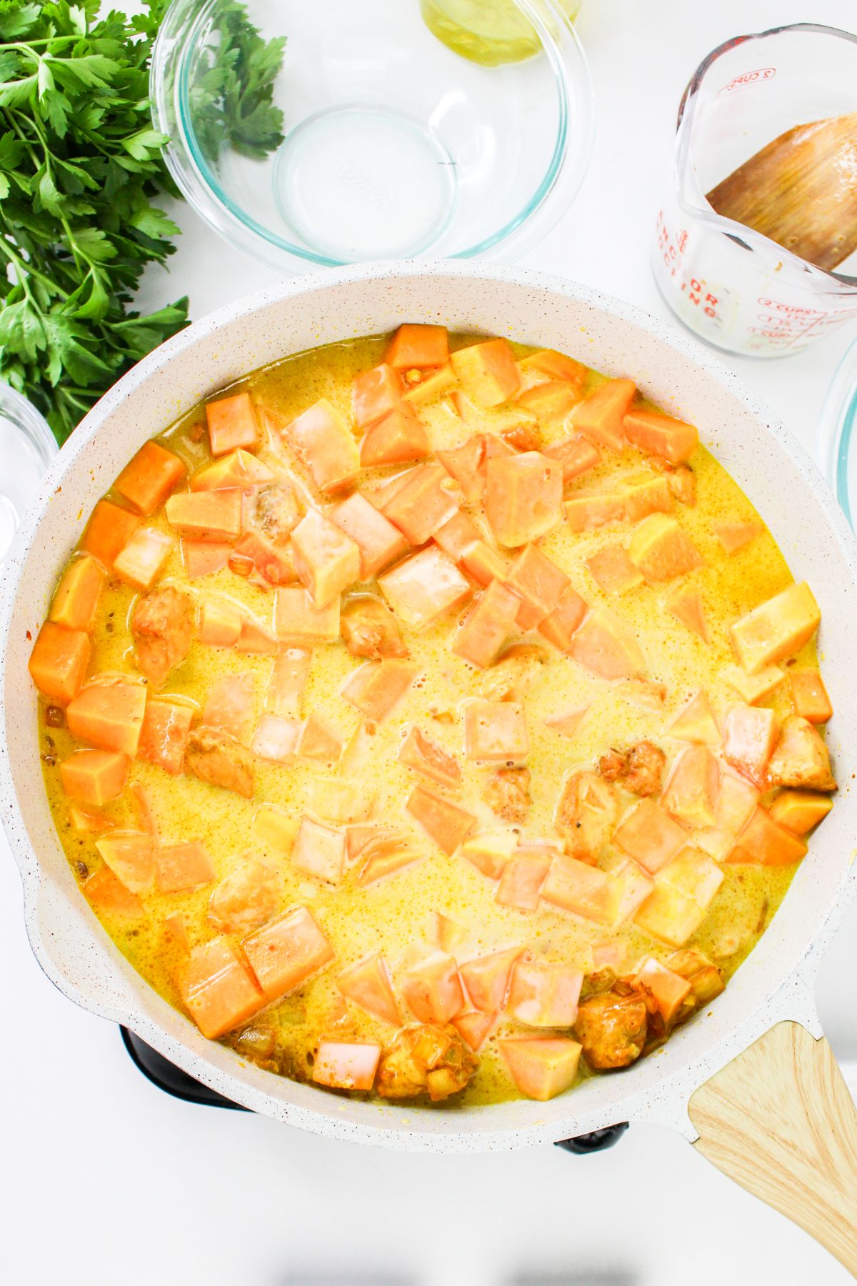 Pumpkin cubes being added to a large pot to cook.