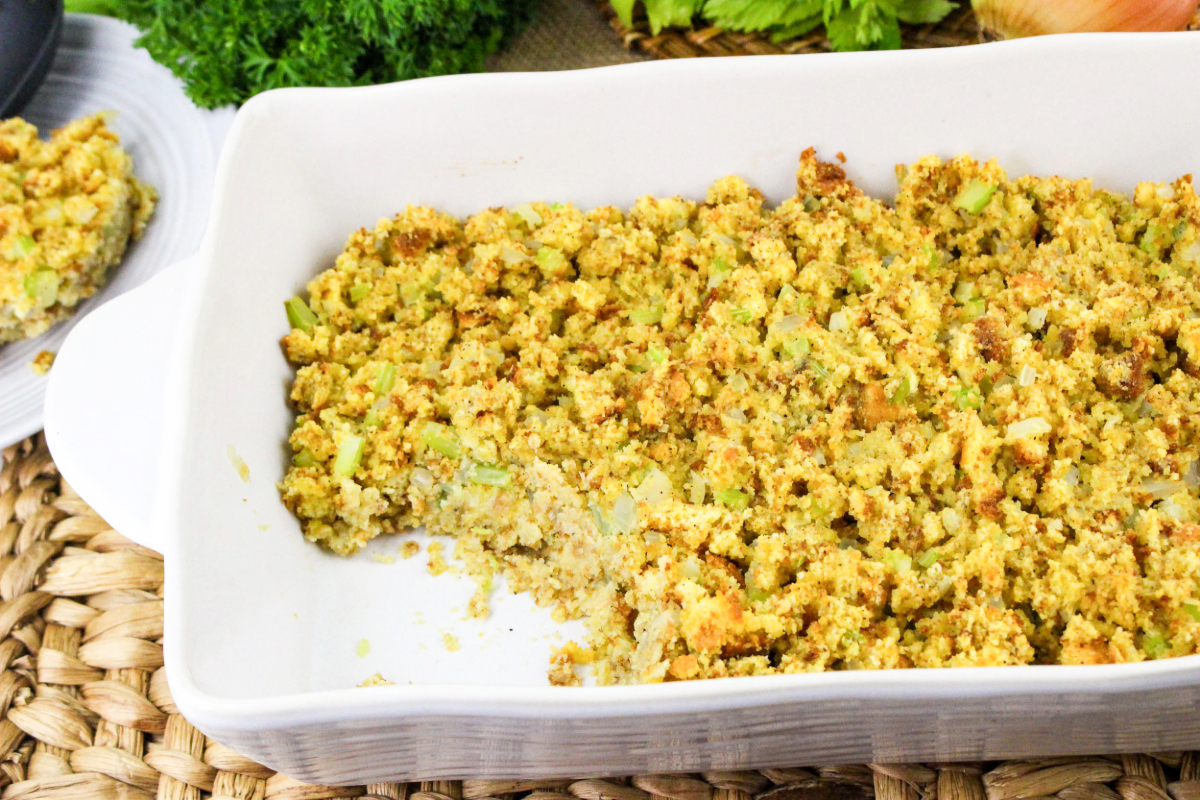 Cornbread dressing in a casseorle dish with a serving missing.