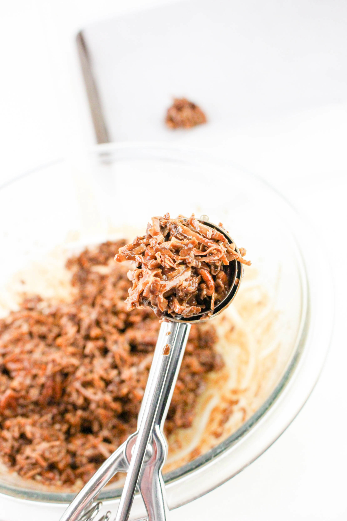 Coconut and chocolate being scooped with a cookie scoop.