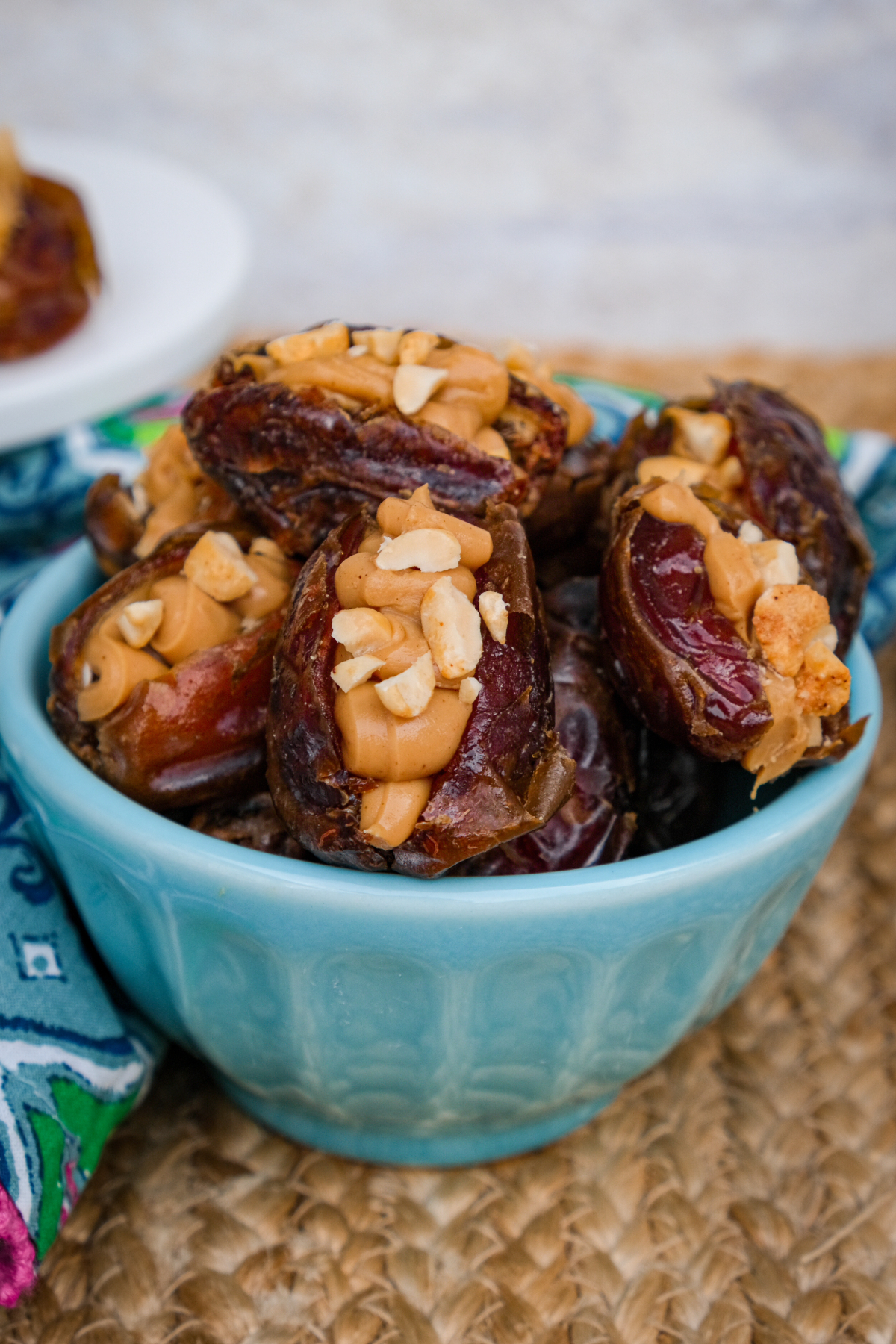 Dates stuffed with peanut butter and topped with chopped peanuts in a bowl. 