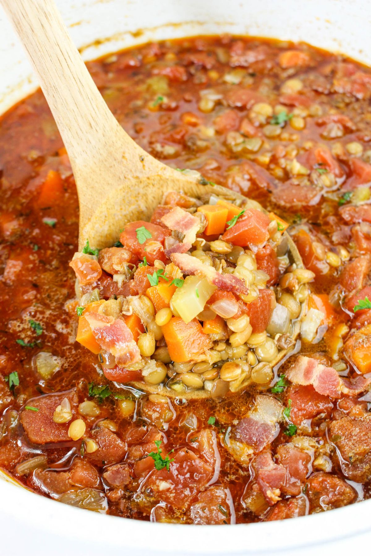 Wooden spoonful of bacon lentil soup.