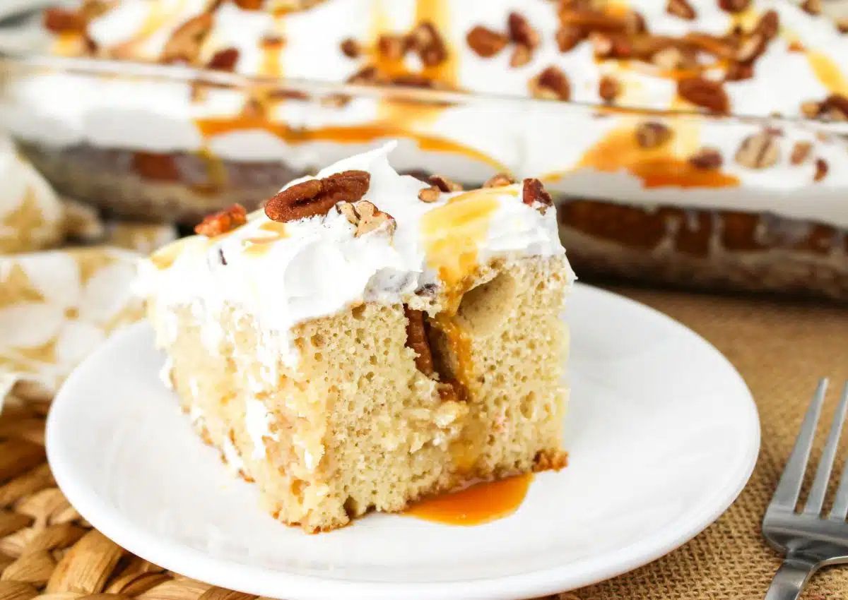 Piece of butter pecan poke cake on plate.