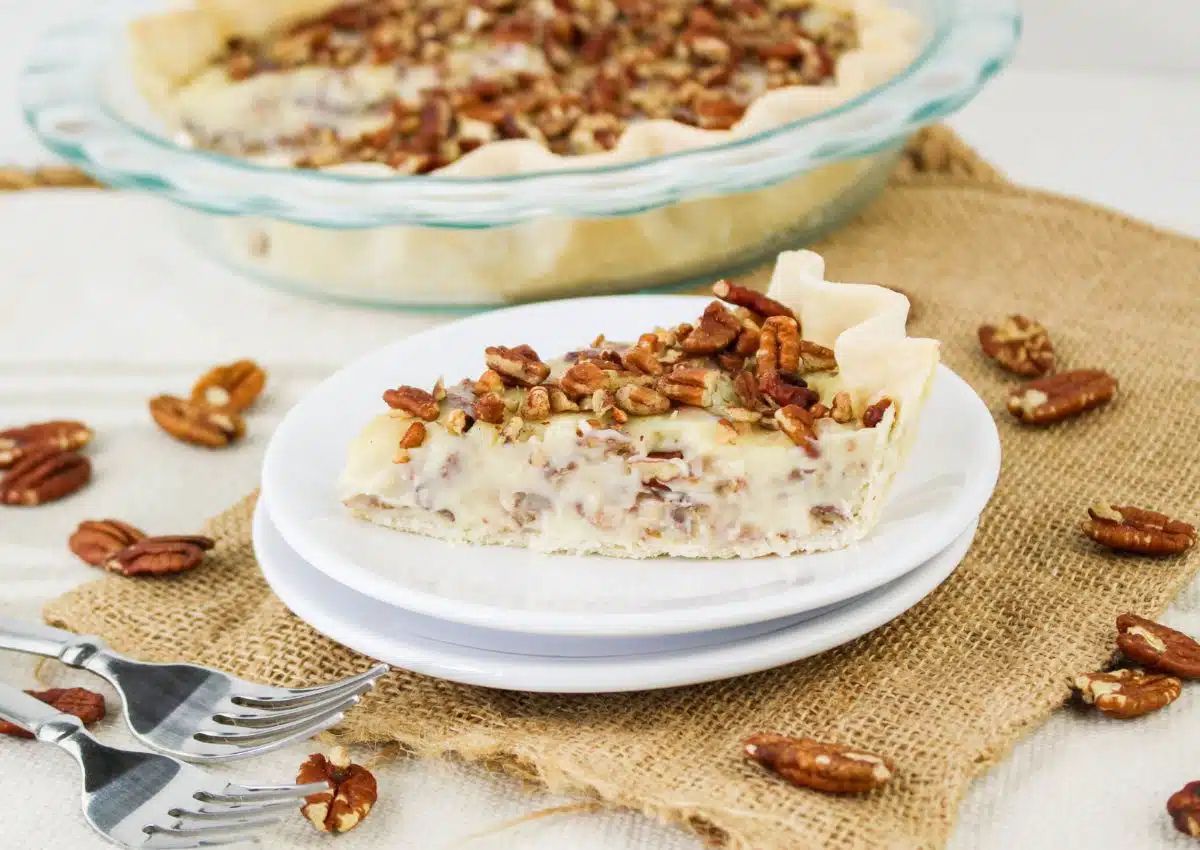 Slice of creamy pecan pie on plate.
