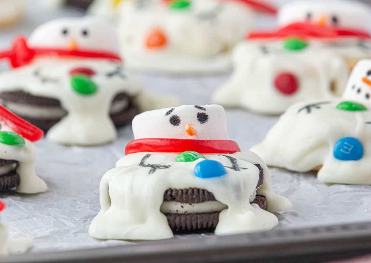 Melted snowman cookies on a parchment lined baking sheet.