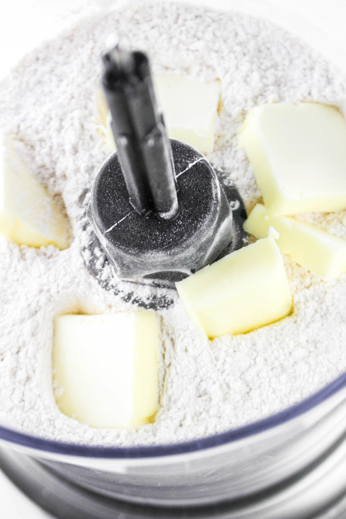Sliced butter with flour mixture in a food processor before mixing.